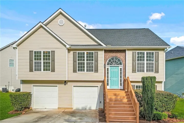 Two-story residence featuring light-colored siding, a dark shingle roof, and an arched brick entryway