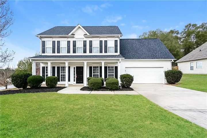 Two-story residence featuring a covered front porch, white siding, and a dark shingle roof