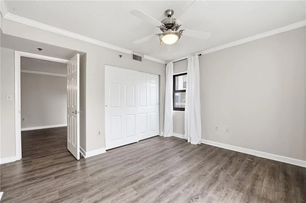 Unfurnished bedroom with crown molding, a closet, dark wood-style flooring, a ceiling fan, and a textured ceiling