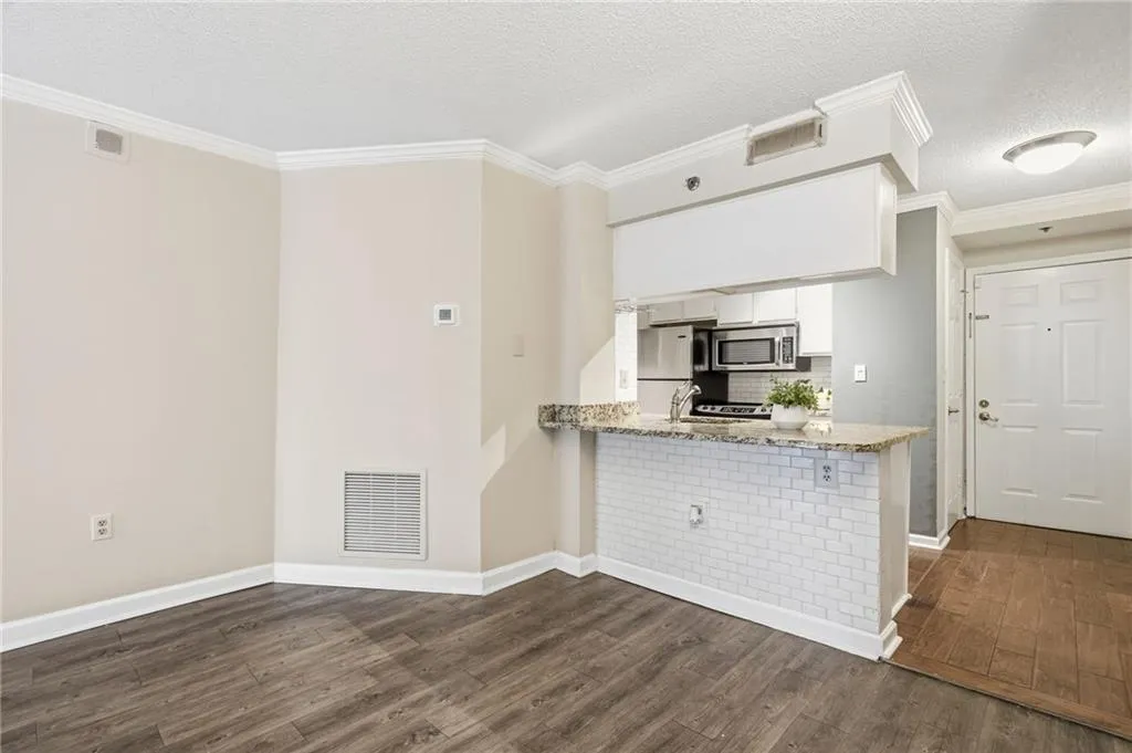 Kitchen featuring white cabinetry, crown molding, decorative backsplash, a peninsula, and light stone countertops