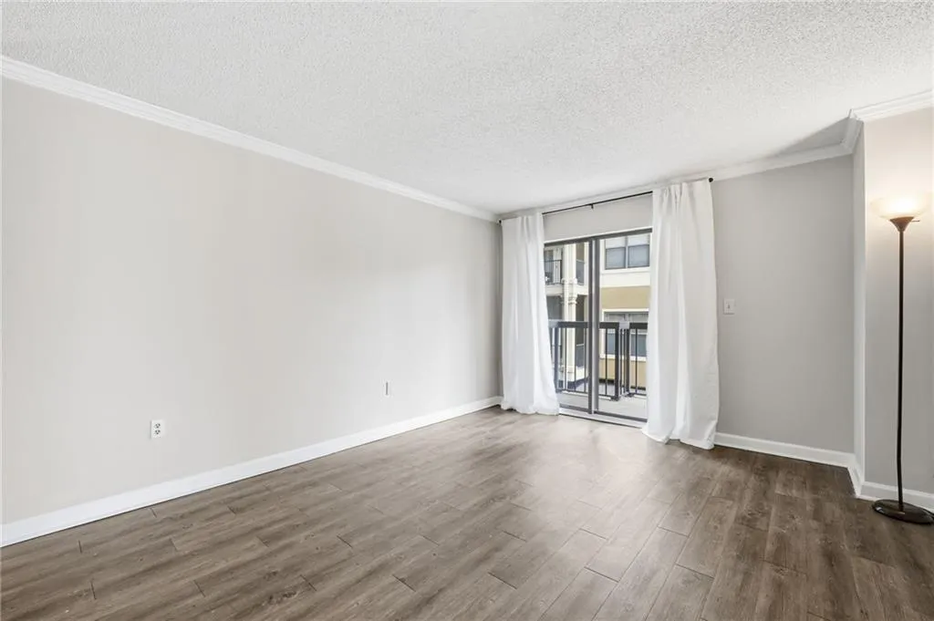 Empty room with ornamental molding, a textured ceiling, and dark wood-type flooring