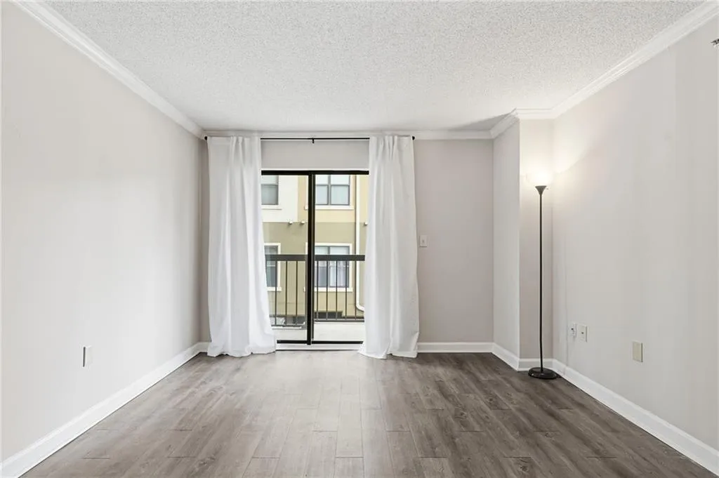 Empty room featuring ornamental molding, dark wood-style floors, and a textured ceiling