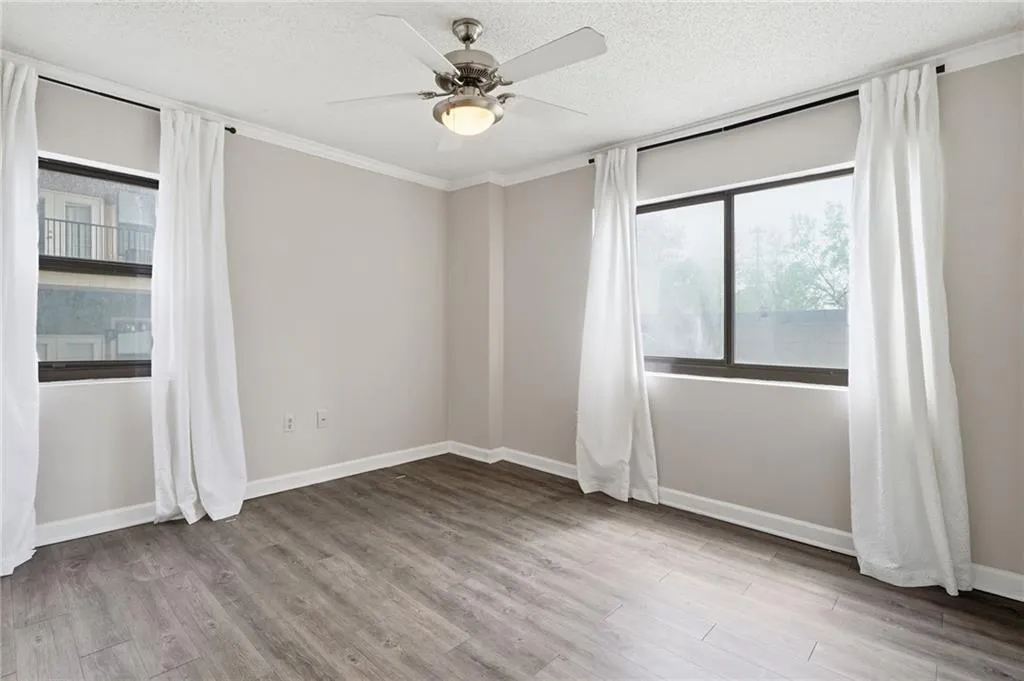 Unfurnished room with light wood-style floors, ornamental molding, ceiling fan, and a textured ceiling