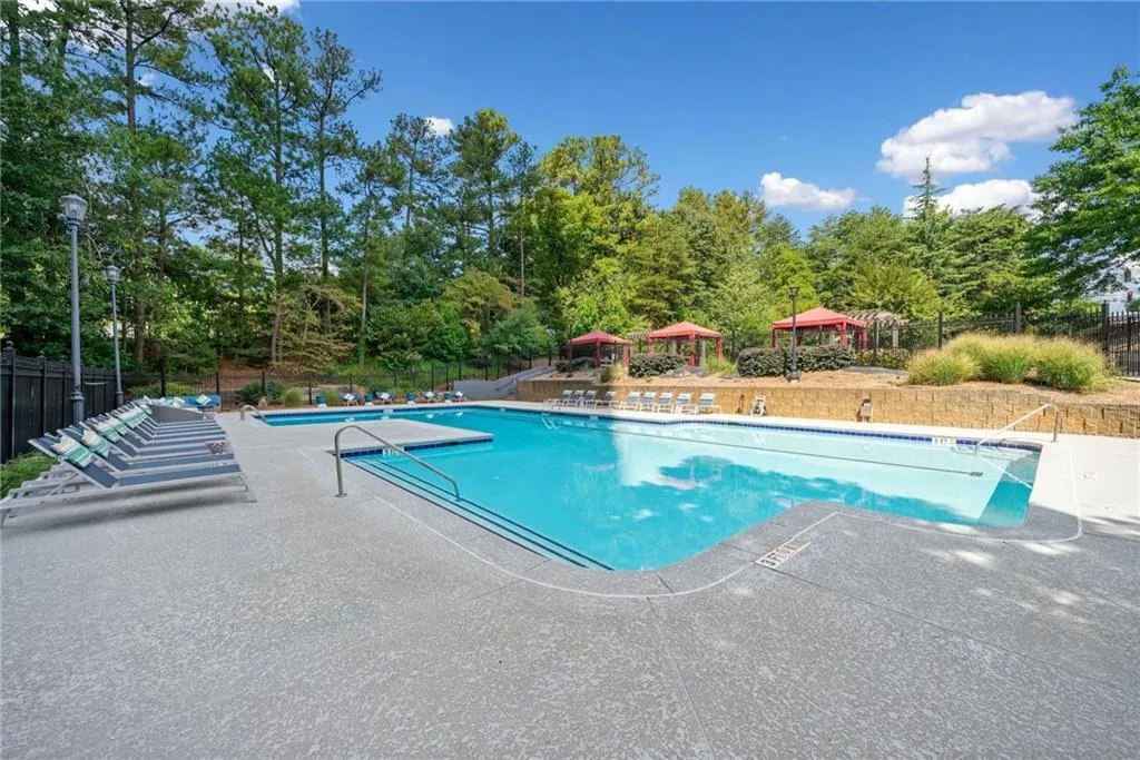 Community pool featuring a patio area and view of wooded area