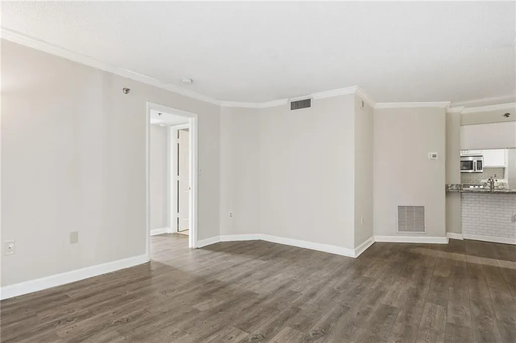Spare room with ornamental molding and dark wood-style flooring