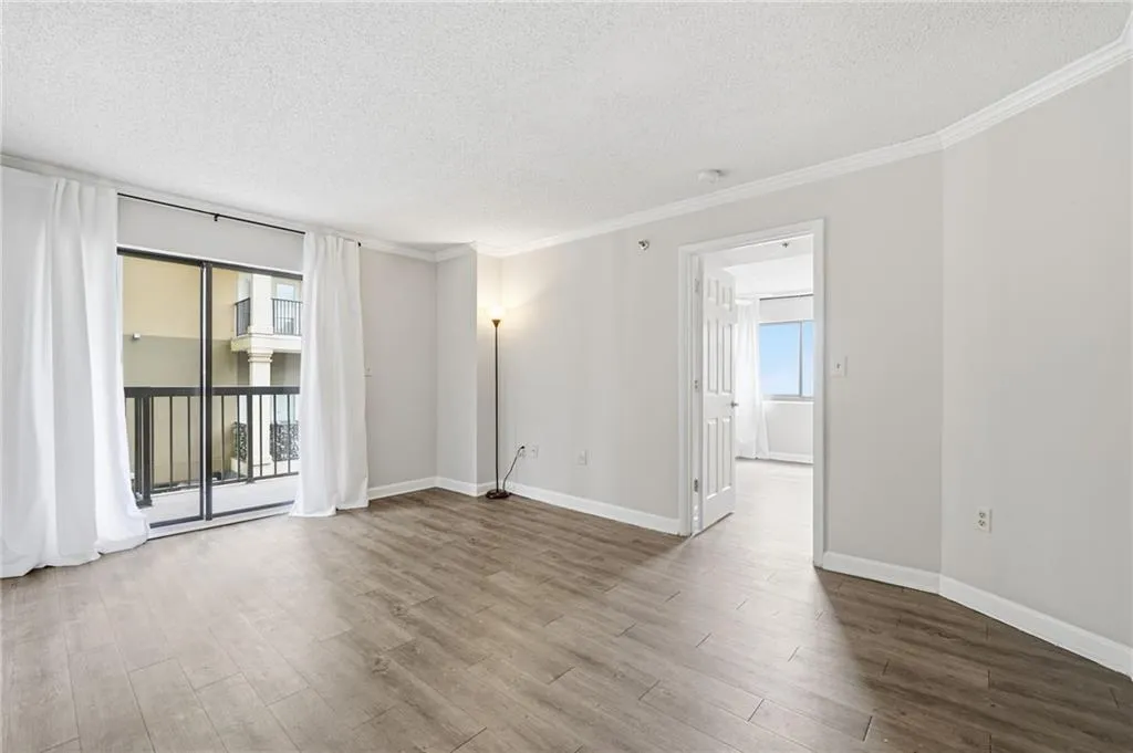 Empty room with a textured ceiling, ornamental molding, wood finished floors, and healthy amount of natural light