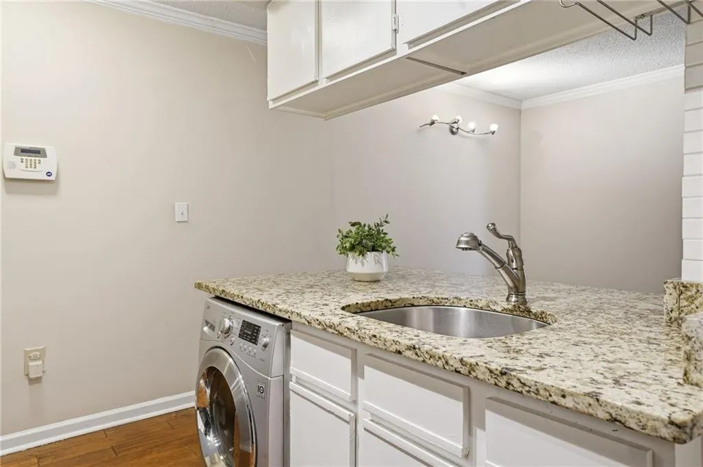 Laundry area featuring washer / dryer, crown molding, dark wood-style flooring, a textured ceiling, and cabinet space