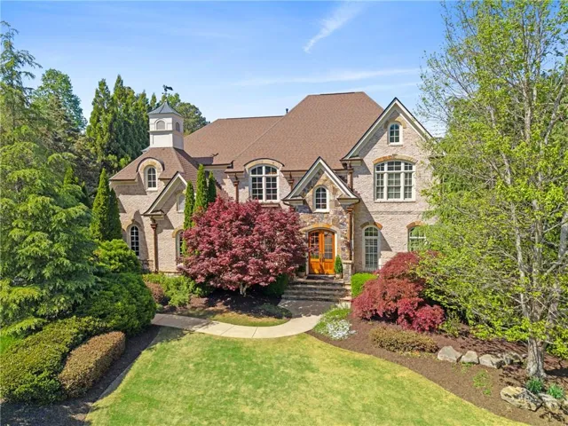 Stately brick exterior featuring a cupola with a weather vane, multiple gables, arched windows, and a hardwood front door