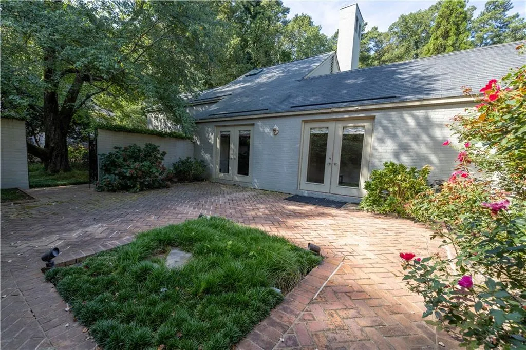 Rear view of property with french doors, brick siding, a chimney, a patio, and roof with shingles