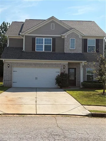 Two-story residence featuring a brick and siding facade, a two-car garage, and a concrete driveway