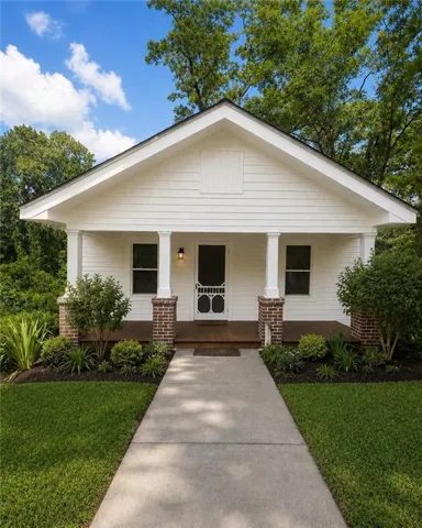White siding exterior with a dark roof and a front porch