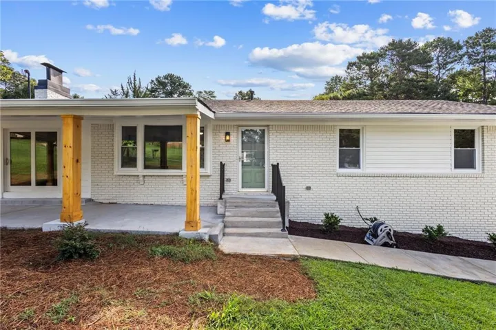 Modern brick ranch featuring a newly renovated front facade with yellow architectural columns, expansive glass sliding doors, and a covered entrance portico