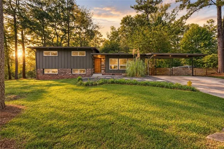 Mid-century modern residence featuring a dark panel exterior, brick accents, and multiple windows