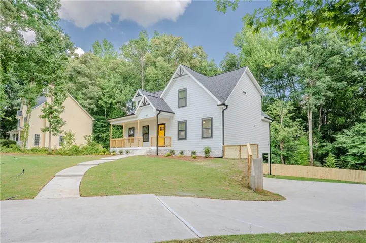 Contemporary farmhouse exterior with white siding, dark trim windows, and a vibrant yellow front door