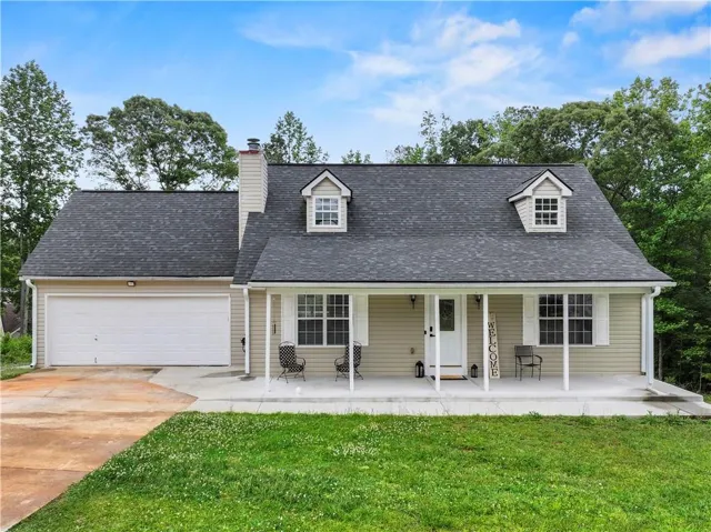 New england style home with covered porch, driveway, a garage, a front lawn, and a shingled roof