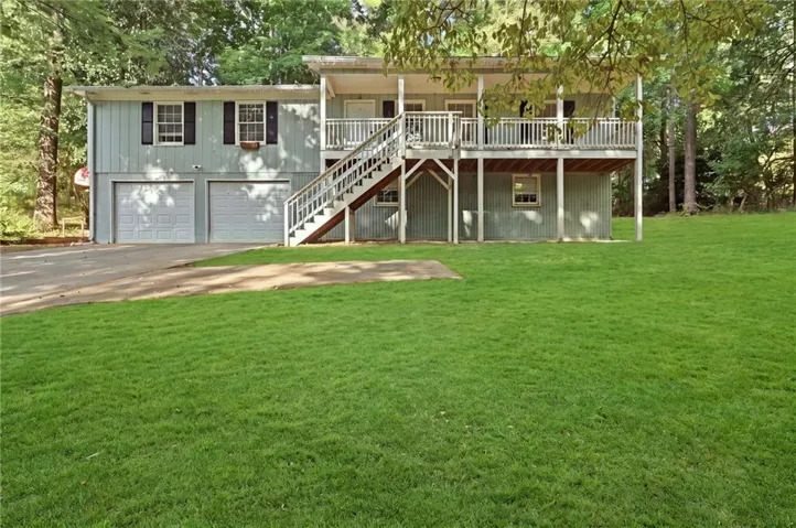 Light blue exterior with white trim, two-car garage, upper-level balcony, and exterior staircase