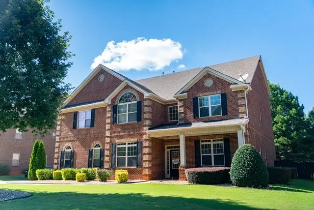 View of front facade featuring a front lawn, brick siding, and a porch