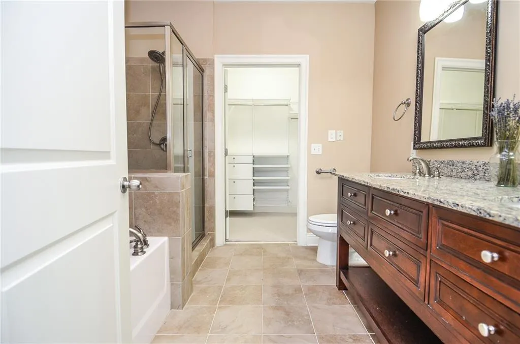 Full bathroom featuring vanity, shower with separate bathtub, toilet, and tile patterned flooring