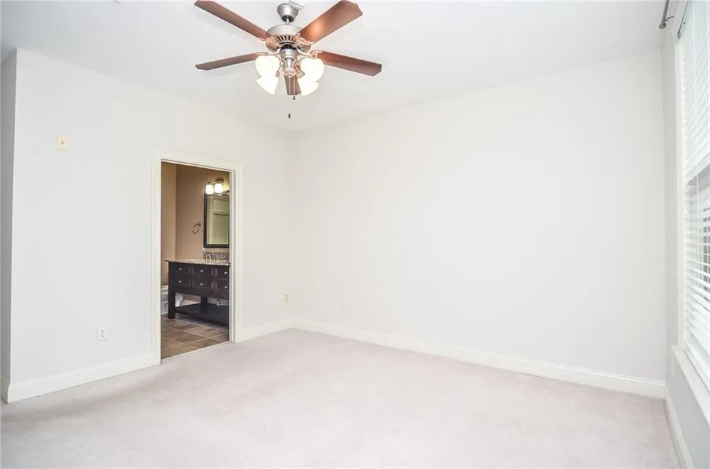 Carpeted spare room with a wealth of natural light and ceiling fan