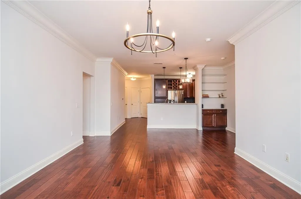 Unfurnished living room with ornamental molding, dark hardwood / wood-style floors, and a notable chandelier