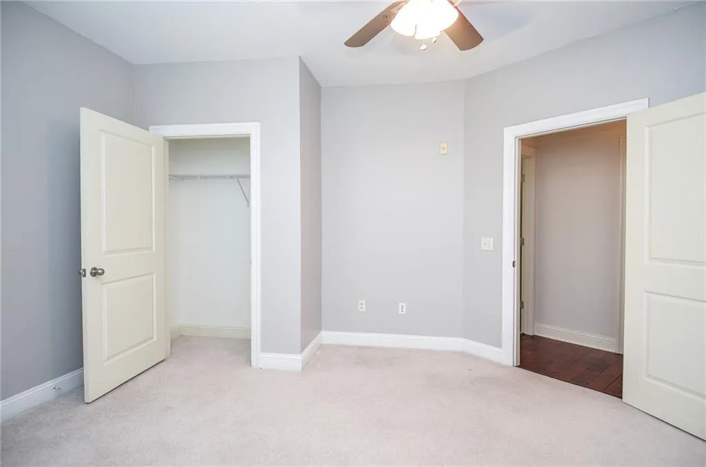 Unfurnished bedroom featuring ceiling fan, light colored carpet, and a closet