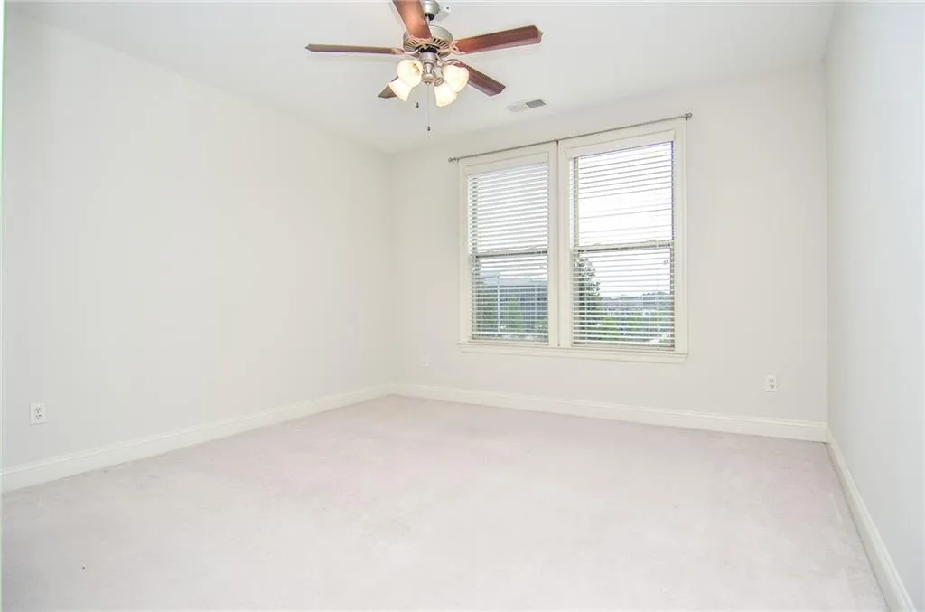 Carpeted spare room featuring ceiling fan