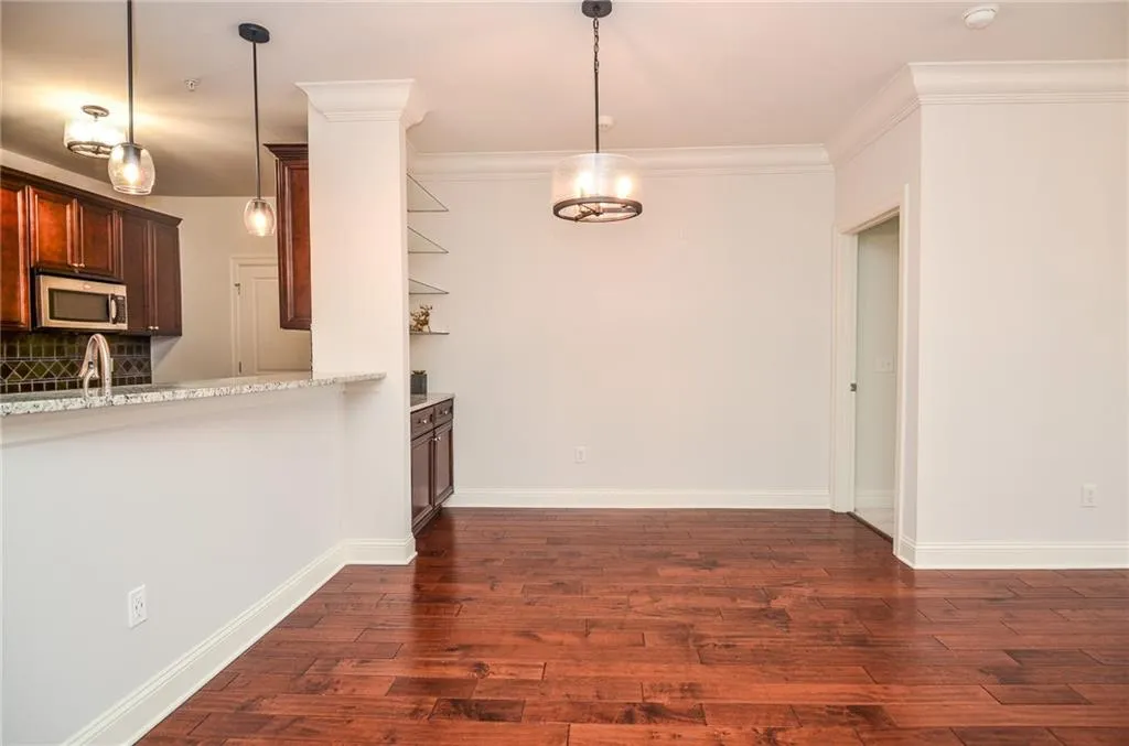 Kitchen with pendant lighting, light stone counters, sink, dark hardwood / wood-style flooring, and ornamental molding