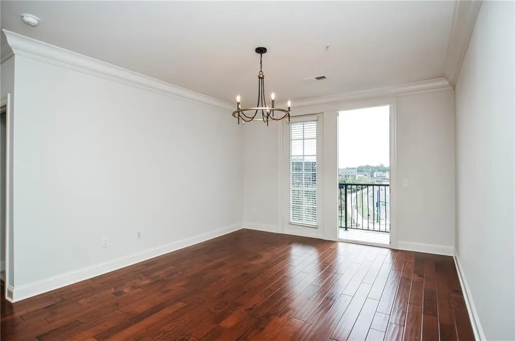 Spare room featuring a notable chandelier, dark hardwood / wood-style floors, and crown molding