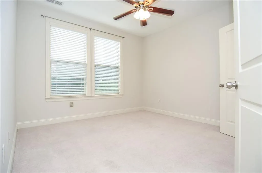 Carpeted empty room with a wealth of natural light and ceiling fan