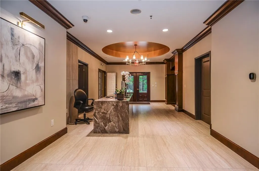 Hall featuring a tray ceiling, crown molding, and a chandelier
