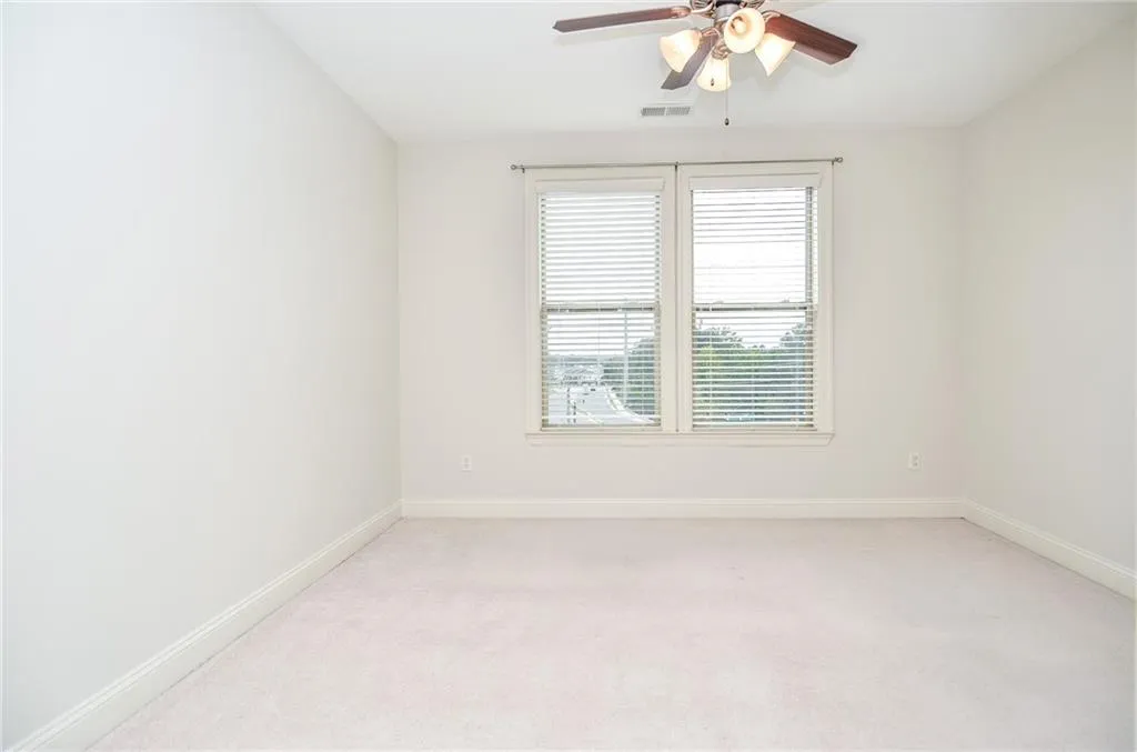 Carpeted empty room featuring ceiling fan