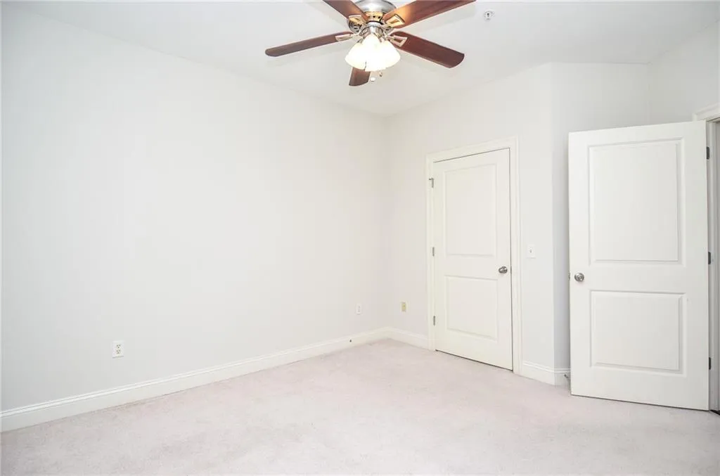 Unfurnished bedroom with ceiling fan and light colored carpet