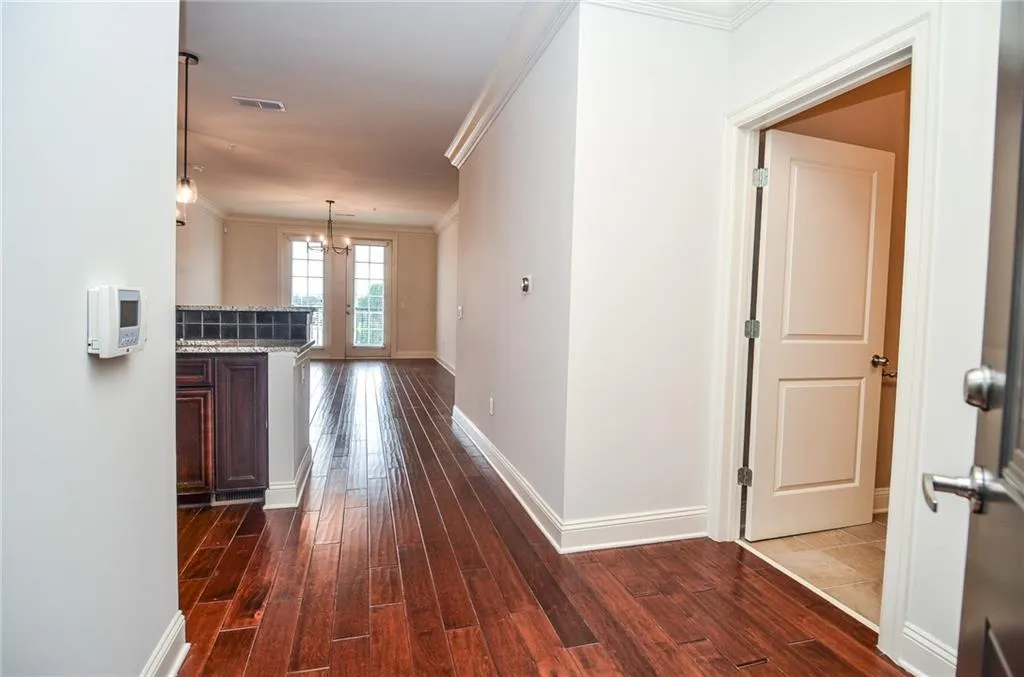 Hall featuring crown molding, an inviting chandelier, and dark wood-type flooring