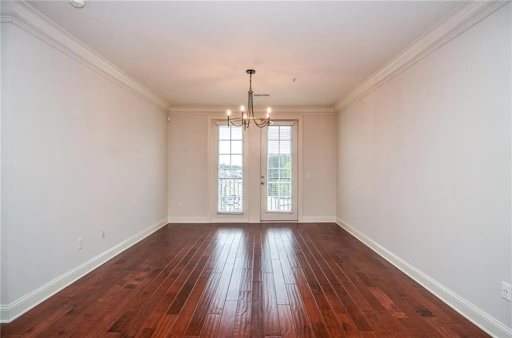Spare room with ornamental molding, dark hardwood / wood-style flooring, and a notable chandelier