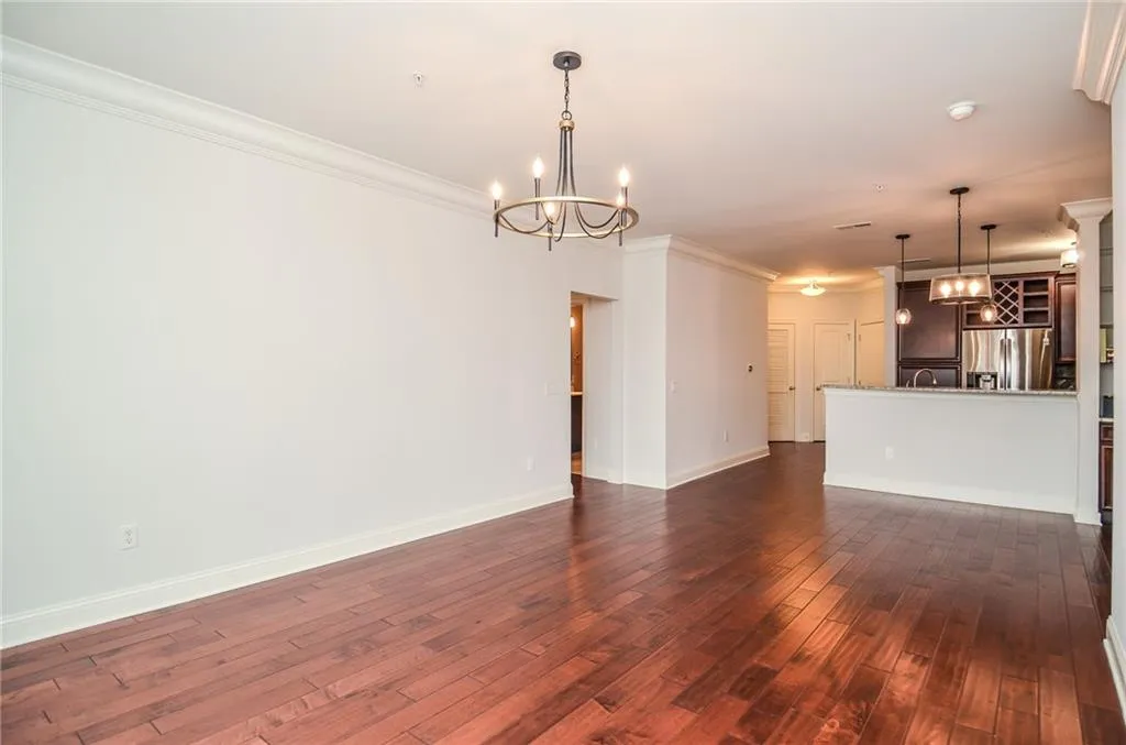 Unfurnished living room with a notable chandelier, crown molding, and dark wood-type flooring