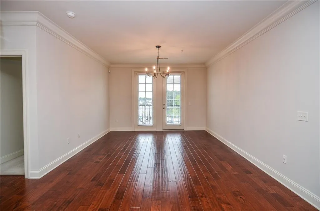 Unfurnished room with a notable chandelier, crown molding, and dark hardwood / wood-style flooring