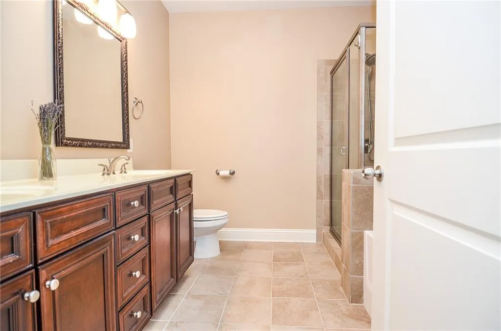 Bathroom with tile patterned floors, a shower with shower door, vanity, and toilet
