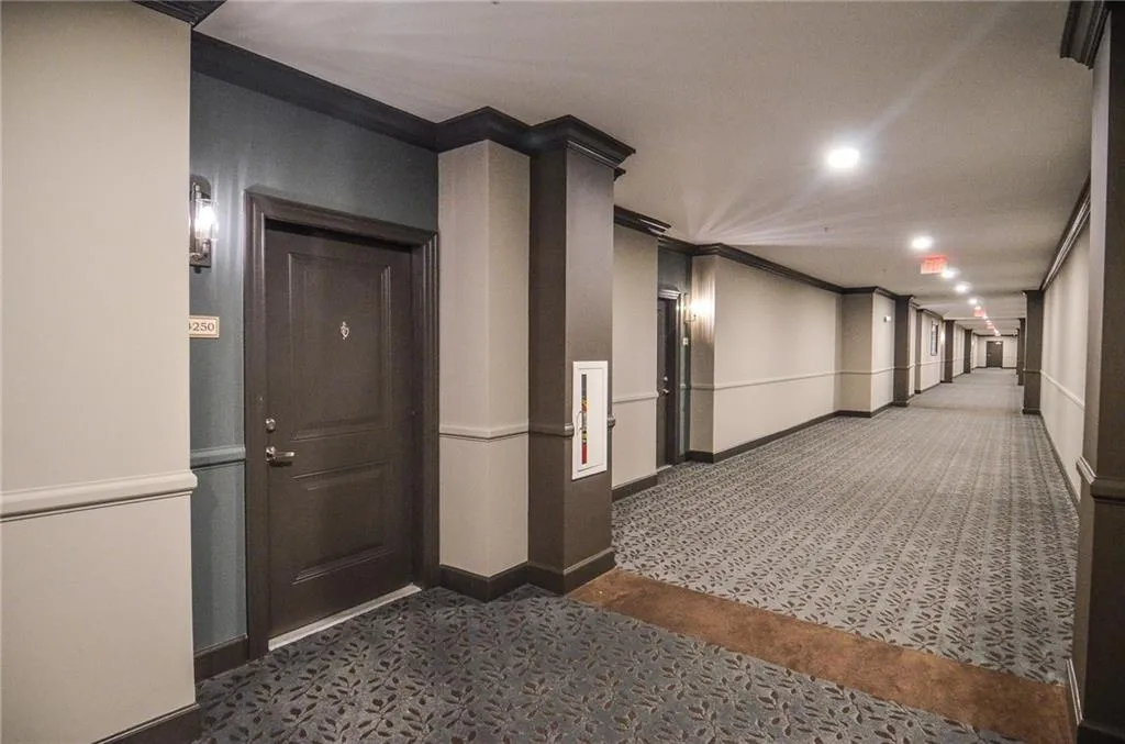 Corridor featuring dark carpet and ornamental molding