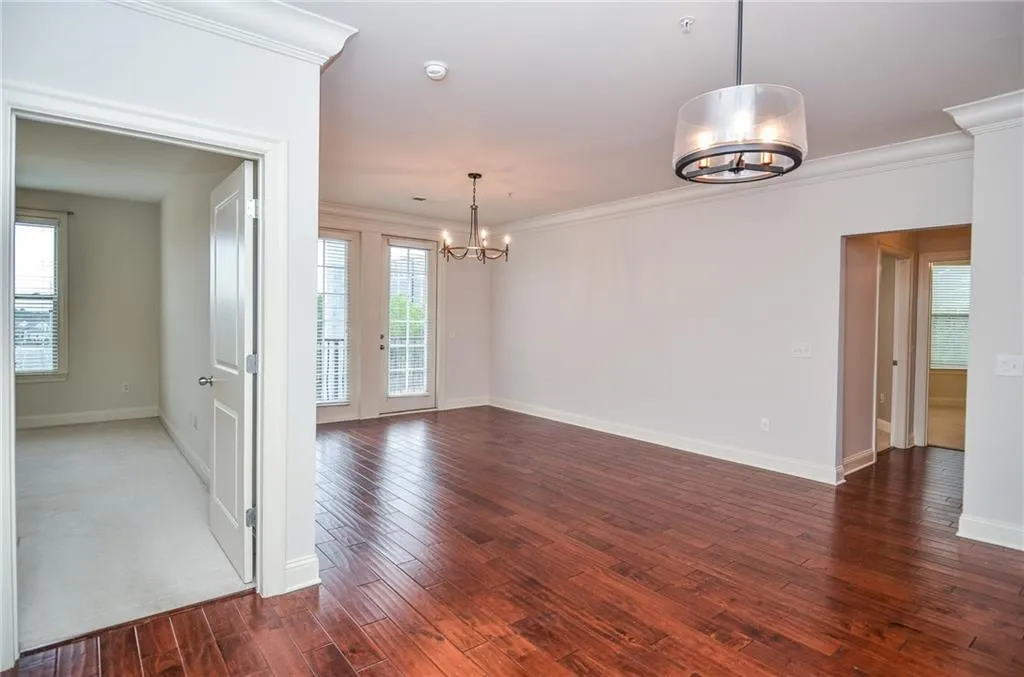 Empty room featuring ornamental molding, dark wood-type flooring, and plenty of natural light
