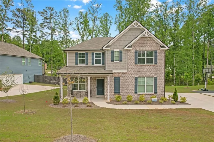 Craftsman-style home with a front yard, a porch, brick siding, driveway, and roof with shingles