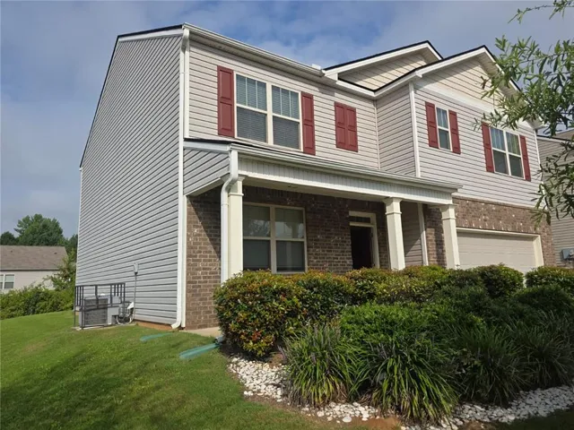 Two-story residence featuring a brick and siding exterior, covered porch entrance with columns, and an integrated garage