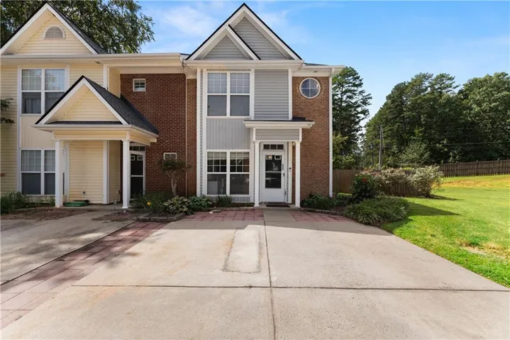 Brick and siding exterior featuring gabled rooflines, a round window, and a concrete driveway