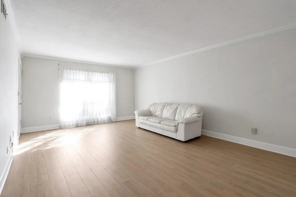 Living room featuring hardwood / wood-style flooring and crown molding - virtually staged.