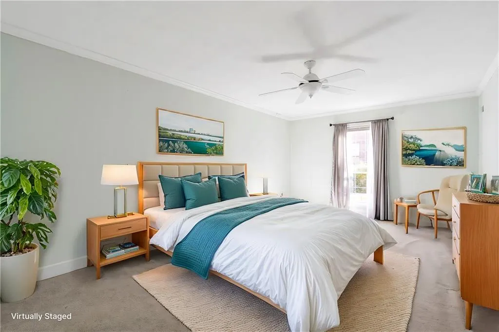 Carpeted bedroom with ceiling fan and ornamental molding - virtually staged.