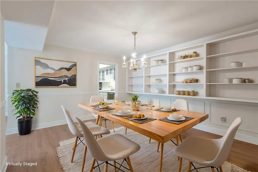 Dining room featuring an inviting chandelier, ornamental molding, sink, and light hardwood / wood-style flooring - virtually staged.