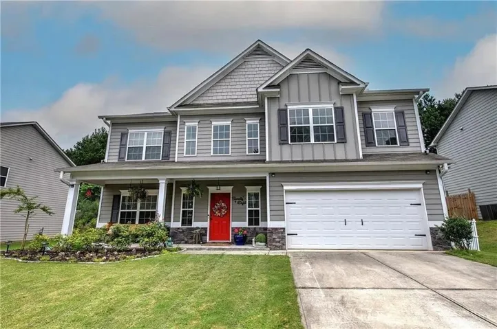 Craftsman inspired home featuring covered porch, a garage, board and batten siding, stone siding, and a front yard