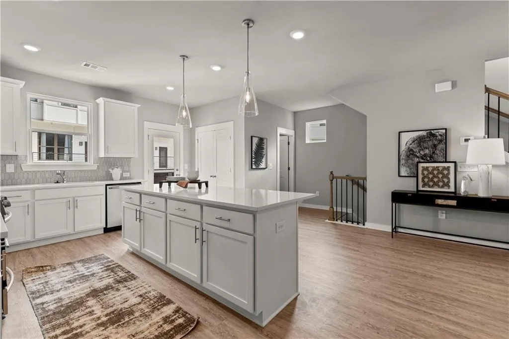 Kitchen featuring white cabinetry, decorative light fixtures, tasteful backsplash, light wood finished floors, and a center island