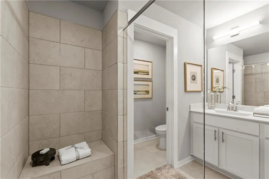 Bathroom featuring vanity, tiled shower, and light tile patterned flooring
