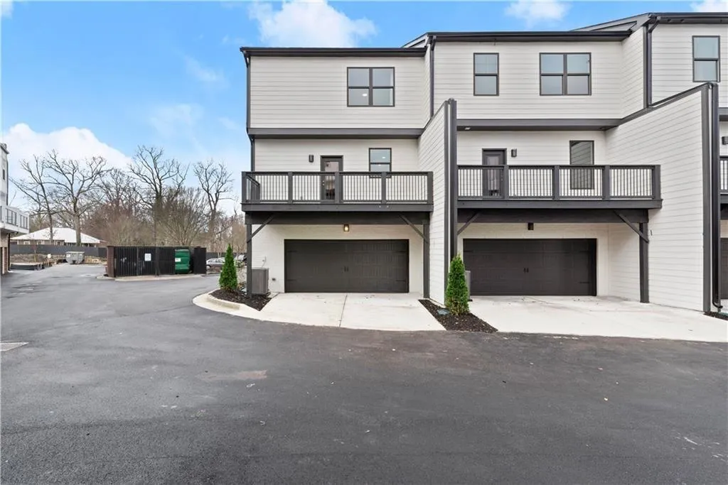 Back of house featuring driveway, a garage, and a balcony