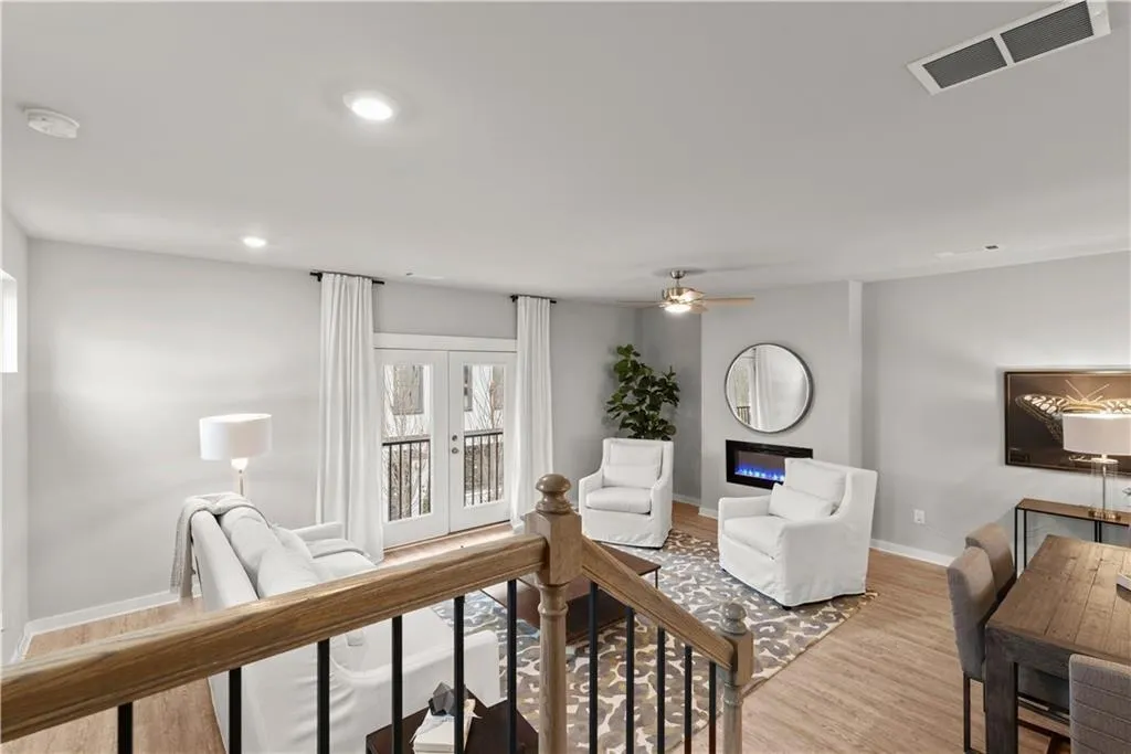 Living room featuring light wood finished floors, recessed lighting, french doors, a glass covered fireplace, and a ceiling fan